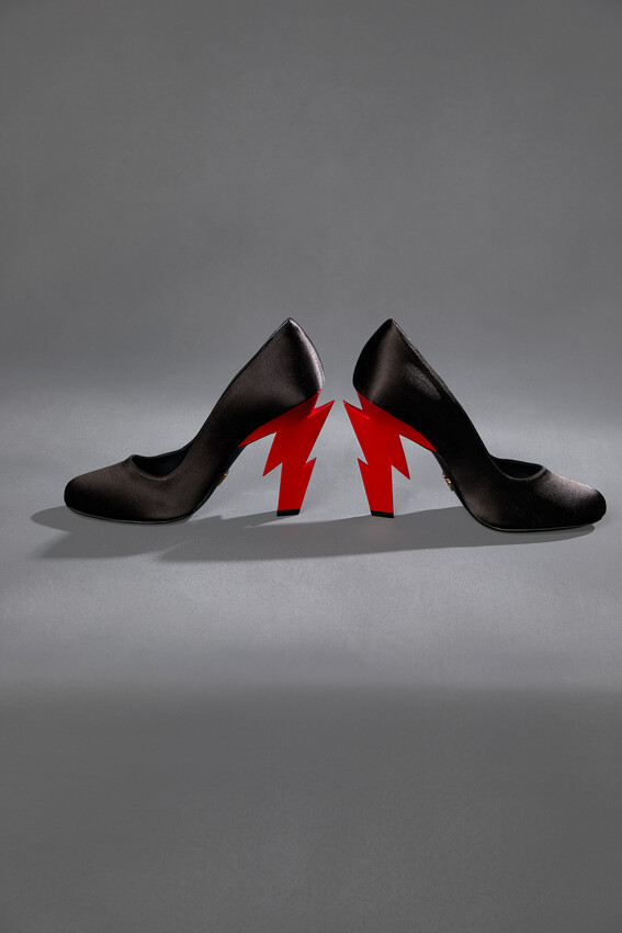 A pair of black satin high heels with jagged red lightning bolts as the heels.