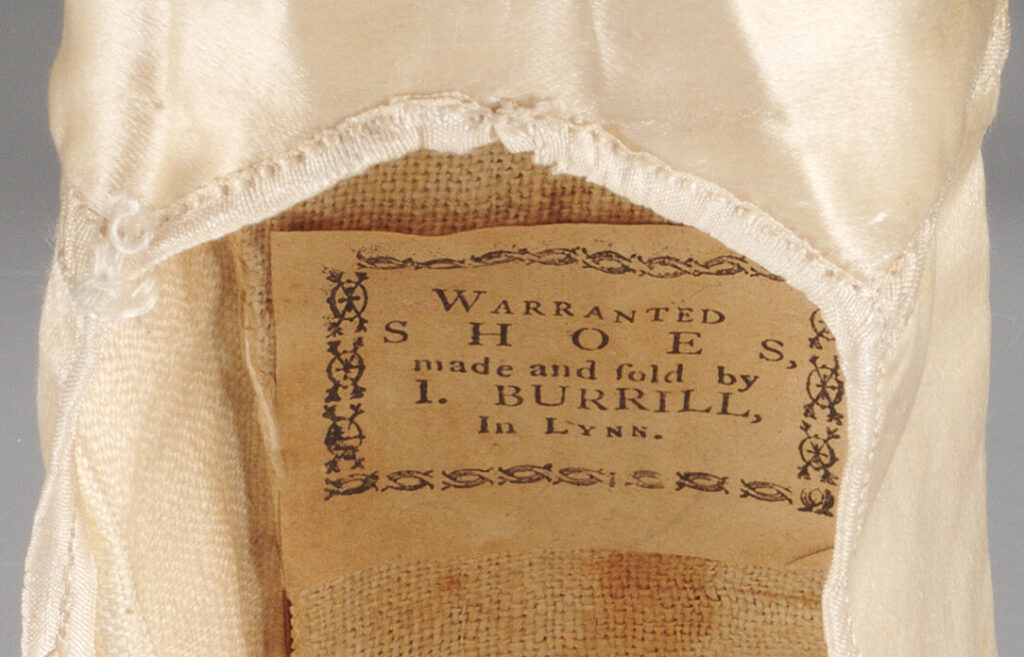 A label inside of a shoe reads, “Warranted shoes, made and sold by I. Burrill, In Lynn.”